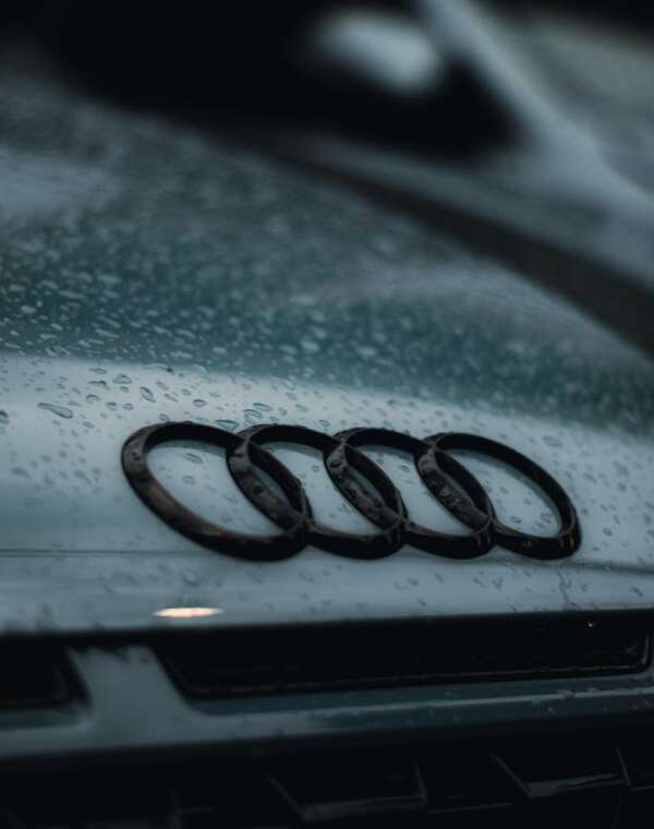 Raindrops on the hood of an Audi car, showcasing the brand's emblem.